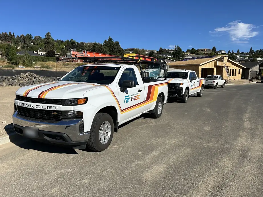Two Farwest pickups with sunset stripe livery and ladder racks parked on a new construction street